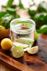 On a wooden table, the decorative tropical cold beverage 'Lemonade' with sliced Lemon.