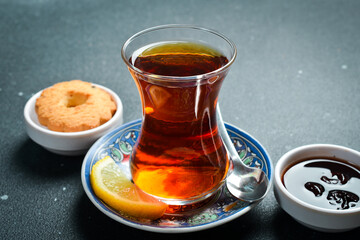 Traditional Turkish serving of aromatic tea in a glass. On a black stone background.