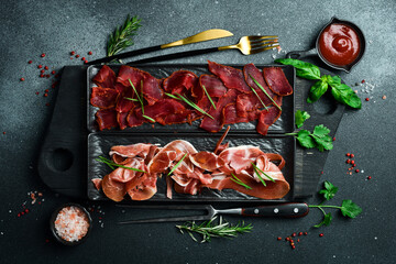 Antipasto Prosciutto and basturma, bacon, sliced ​​on a plate. Appetizers for beer or wine....
