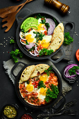 Fried eggs with vegetables: tomatoes, paprika, peppers, onions. Vegetable Shakshuka in a pan. Top view. Free space for your text.