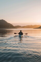 Fototapeta premium Serene Kayaker Enjoys Golden Sunset on Tranquil Mountain Lake