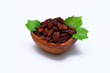 delicious raisins in a wooden bowl with green leaves on a white background