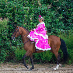 Chica joven ataviada con traje de volantes de Andalucía, paseando a caballo durante la romería del Rocio en Almonte, España © Juanmi
