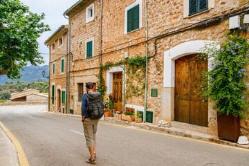 The tourist man walking on the rustic village street lined with charming houses in Fornalutx
