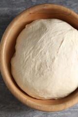 Raw dough in bowl on grey table, top view