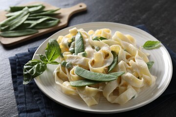Delicious pasta with green peas and creamy sauce on black table