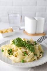 Delicious pasta with green peas served on white table