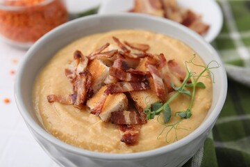 Delicious lentil soup with bacon and croutons on table, closeup