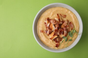 Delicious lentil soup with bacon and croutons on green background, top view. Space for text