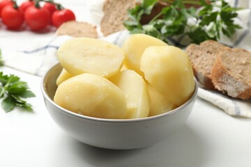 Young boiled potatoes in bowl on white table, closeup