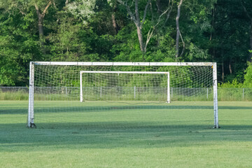 Fototapeta premium Soccer field amateur field, goal post, selective focus, green grass, summer fun sports