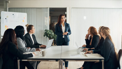 CEO giving a whiteboard presentation to her business team in an office