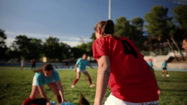 Women's Rugby Players in Intense Scrimmage - Female rugby players in red and blue jerseys engaged in an intense tackle, focusing on the rugby ball during a match.