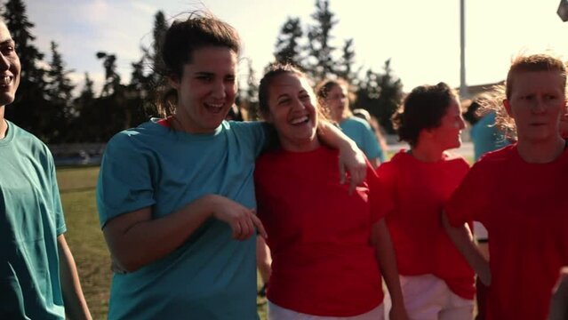Women's Rugby Team Celebrating After Match - Women rugby players in red jerseys celebrate together, smiling and holding a trophy, after a match.