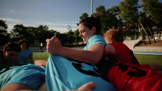 Women's Rugby Teams Engaged in a Scrum - Female rugby players in blue and red jerseys engaged in a scrum on the field during a match.