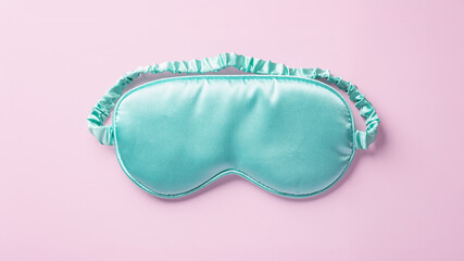 Turquoise silk sleep mask on pastel pink background