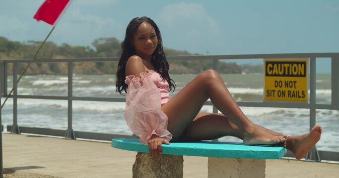 On a bright day at a tropical Caribbean beach, a young girl in a bikini stands by the shore.