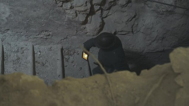 Soldier walking on bunker stair with lamp in hand and keep watching with deep focus.