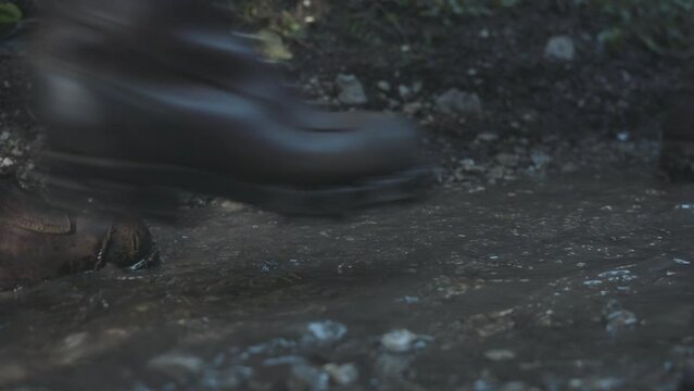 Soldiers marching walking in forest closeup view of boots and water on land.