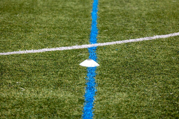 A close-up photo of a white corner flag on a soccer pitch, with visible artificial turf and white...