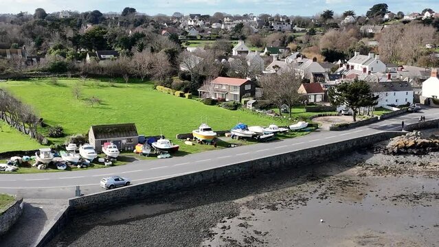 Close circling drone shot on bright day of Bordeaux harbour Guernsey showing roadside and boat storage and views over fields to St Sampson