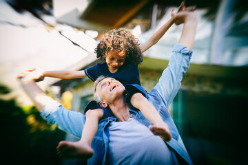 Child, man and sit on shoulders for airplane in backyard for fun, entertainment and development at...