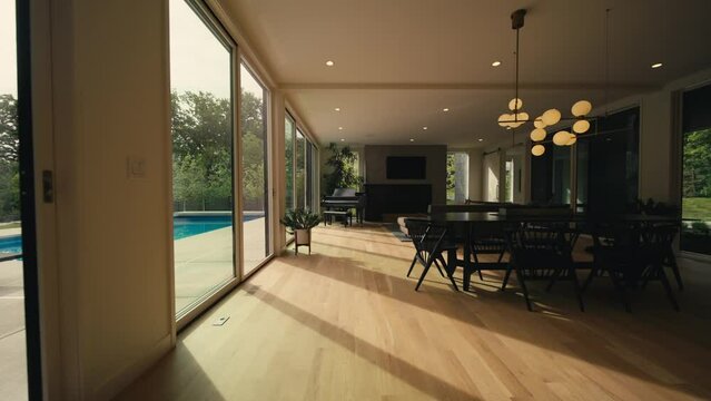 interior living space of a luxury home lined with large sliding doors letting in natural sunlight to showcase a dining area, couch, and a piano