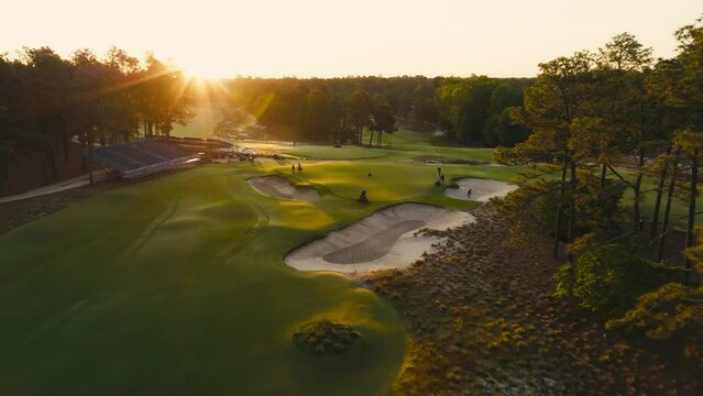 drone shot of golf course maintenance workers or grounds crew prepping a green during sunrise