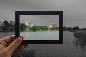 Cropped hand holding a photo frame against cityscape