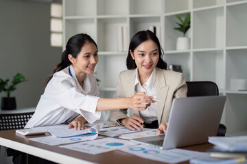 Businesswomen working on laptop and analyzing data in office. Concept of teamwork and collaboration