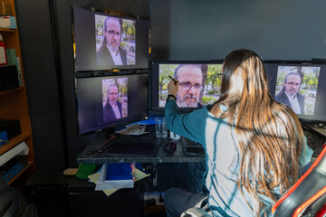 a man sits in front of several computer monitors retouching a photography of himself