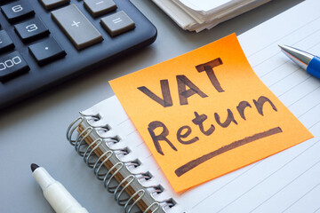 Open ledger and sticky note with words VAT return.