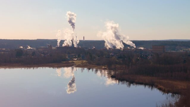  Factory emits noxious greenhouse gases, mirrored reflection in lake. Drone