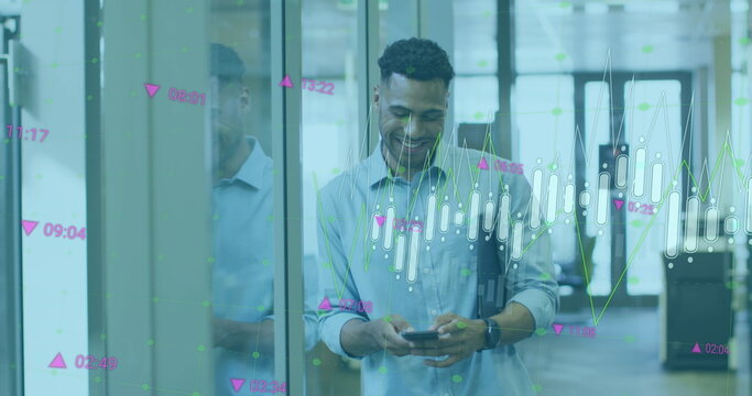 Image of multiple graphs and numbers moving over smiling biracial businessman using mobile phone