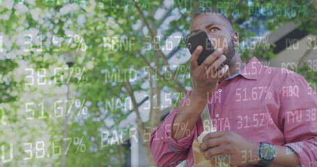 Image of stock market data moving over african american man holding cellphone and eating