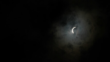Fototapeta premium Solar eclipse with the moon shining through dark clouds in Waco, Texas