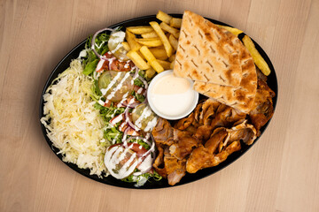 Tray of assorted vegetables, meat sauce, and fries on a wooden table