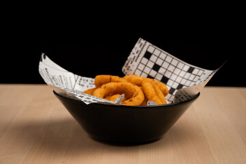 Close-up of crispy onion rings in a black bowl