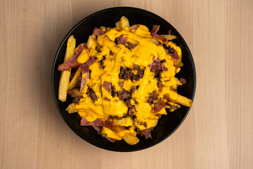 Top view of a black bowl on a wooden table filled with ham and cheese