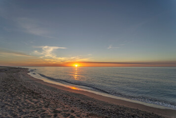 sunrise on the beach of Mojacar is presented with a golden sky and the sun's rays shining on the sea