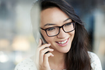 Happy, phone call and Asian woman by window in office for communication, networking or contact. Smile, technology and female creative designer with cellphone for mobile discussion in workplace.