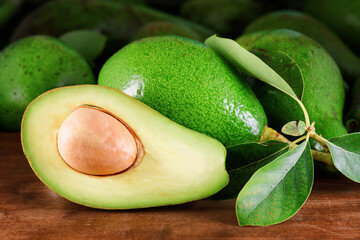 Ripe green avocados with leaves on wooden table