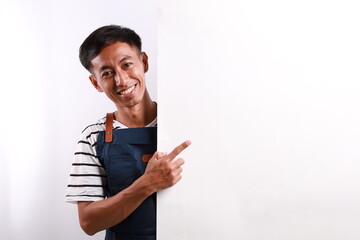 Happy Asian man in apron pointing something on white advertisement board on white background