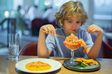 Little boy eating seafood in restaurant. Kid eat Food fish gourmet seafood shrimp in restaurant. Adorable little boy at restaurant having breakfast.