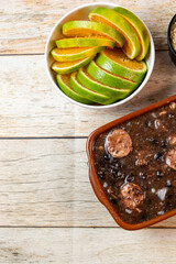 Traditional Brazilian feijoada served in a clay pot with fresh orange and lime slices on the side, showcasing vibrant colors and rich textures.