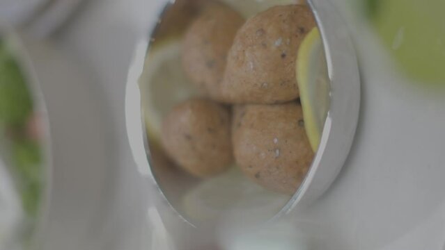 Closeup footage of Lebanese Kibbeh and lemon slices in a plate on the table with blur background