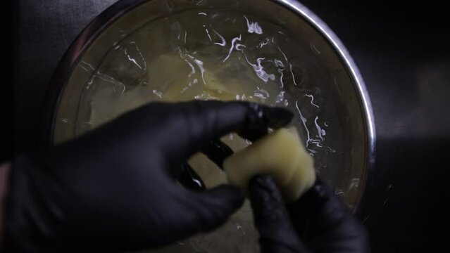 Top-down shot of a guy mixing ice with the thin sliced potato.
