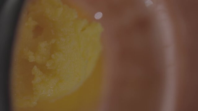 Closeup footage of a table spoon scooping ghee from a bowl, with blur background