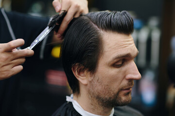 Barber cutting through hair of client with shears