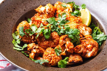 Baked cauliflower in tomato sauce with herbs, white background.
